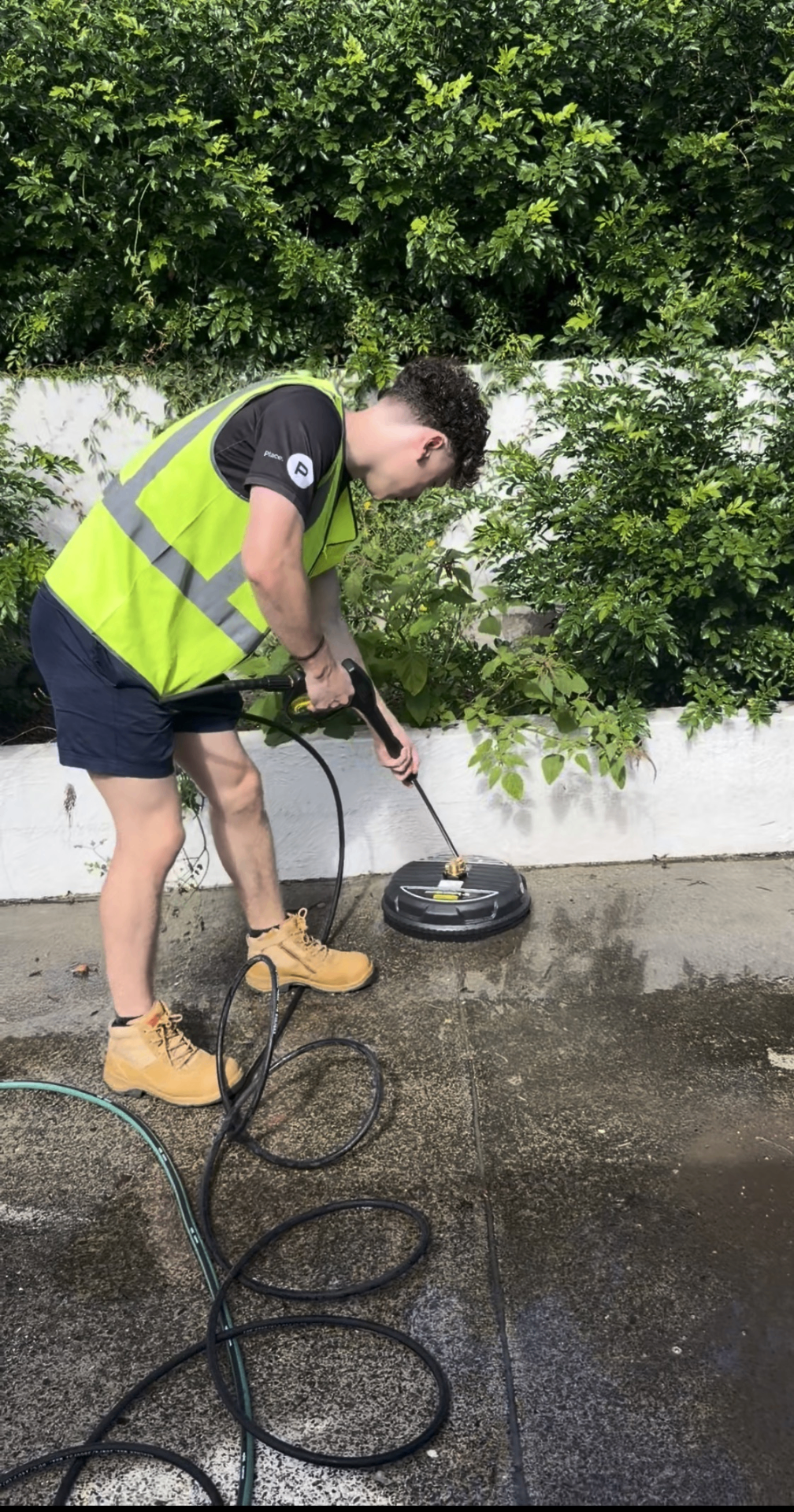 Professional pressure washing a driveway at dusk